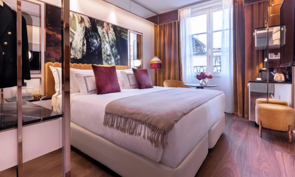 This is an image of a room with a double bed and a big awning window with a nice view.