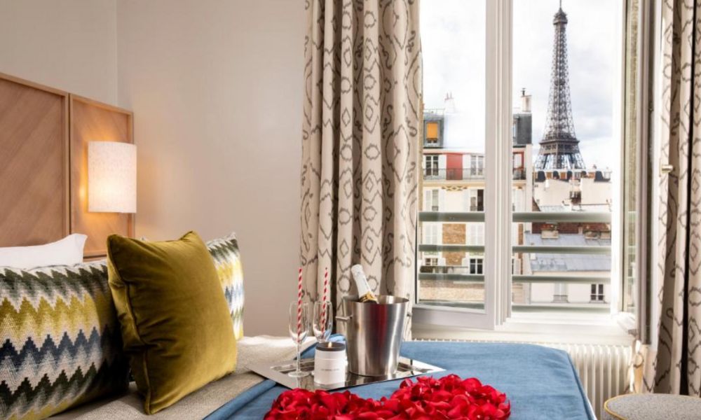This is an image of a double bed with a view of the Eiffel Tower out of the window.