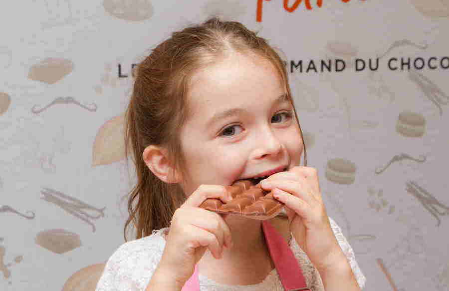 This is an image of a young girl biting into a chocolate bar.