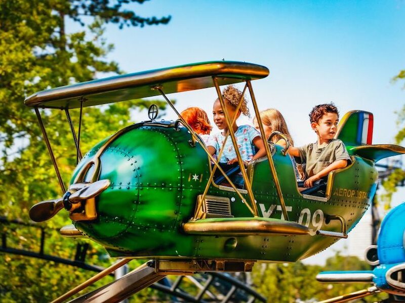 This is an image of four kids in a airplane ride at an amusement park.