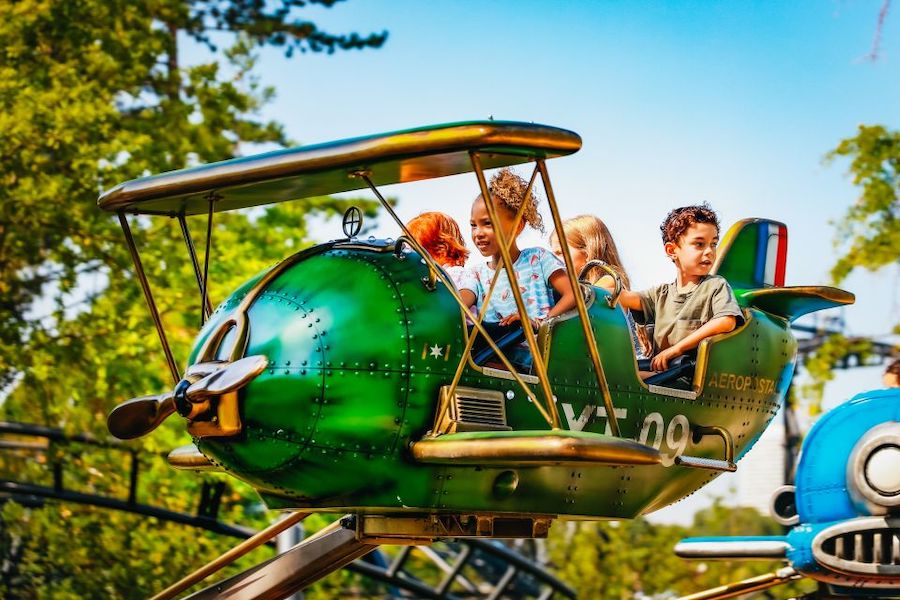 This is an image of four kids in a airplane ride at an amusement park.