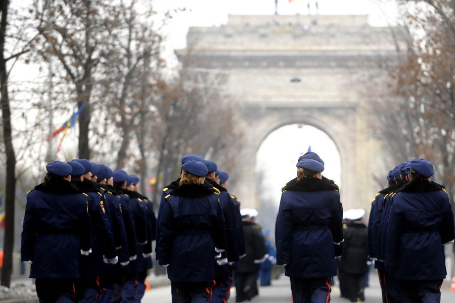 This is an image of the French military walking with the Arc De Triomphe in the distance.