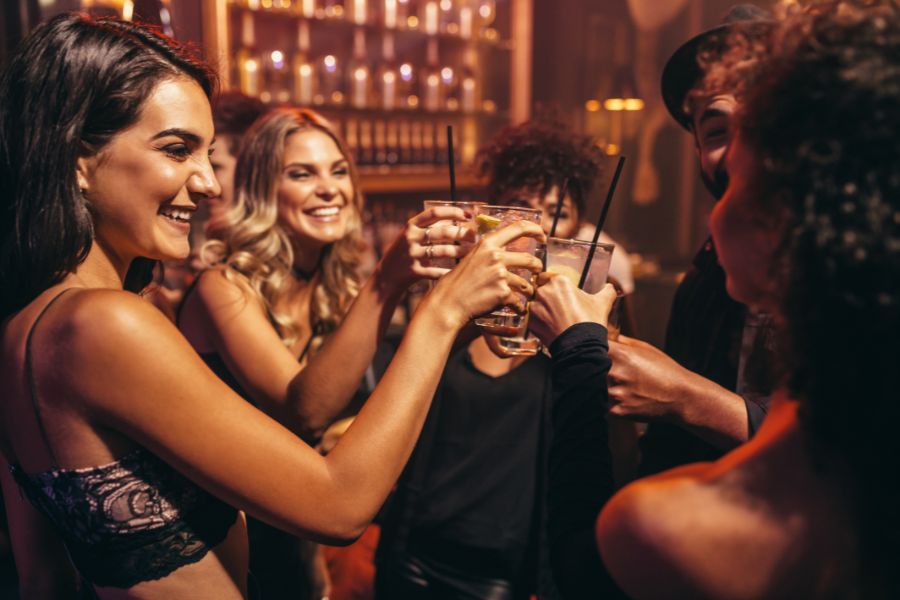 This is an image of a group of people in a bar clinking glasses and smiling.