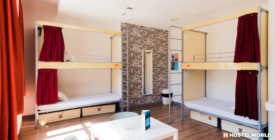 This is an image of a hostel bedroom with multiple bunk beds and simple furniture.