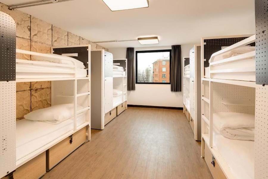This is an image of a hostel bedroom with multiple bunk beds. It is clean and netural in colour palette.