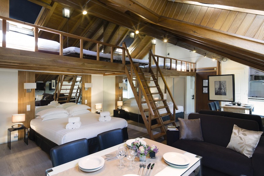 This is an image of a family hotel suite with multiple floors and beds and wooden panelling throughout.