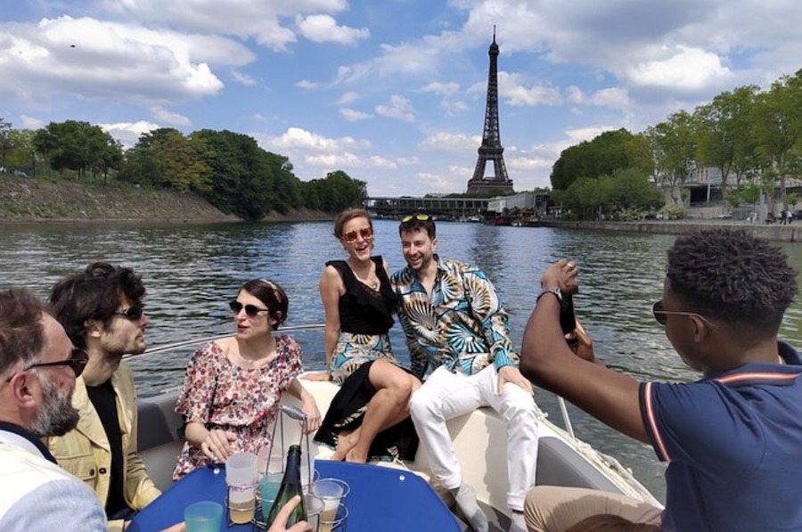 This is an image of a group of people on a boat on the Seine. The Eiffel Tower is in the background.