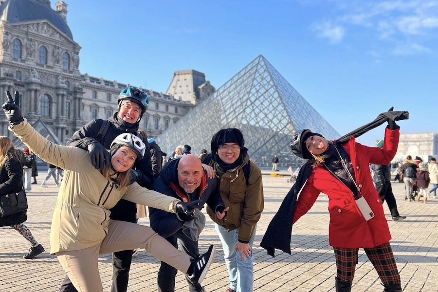 This is an image of a tour group posing in front of the Eiffel Tower and smiling doing silly poses.