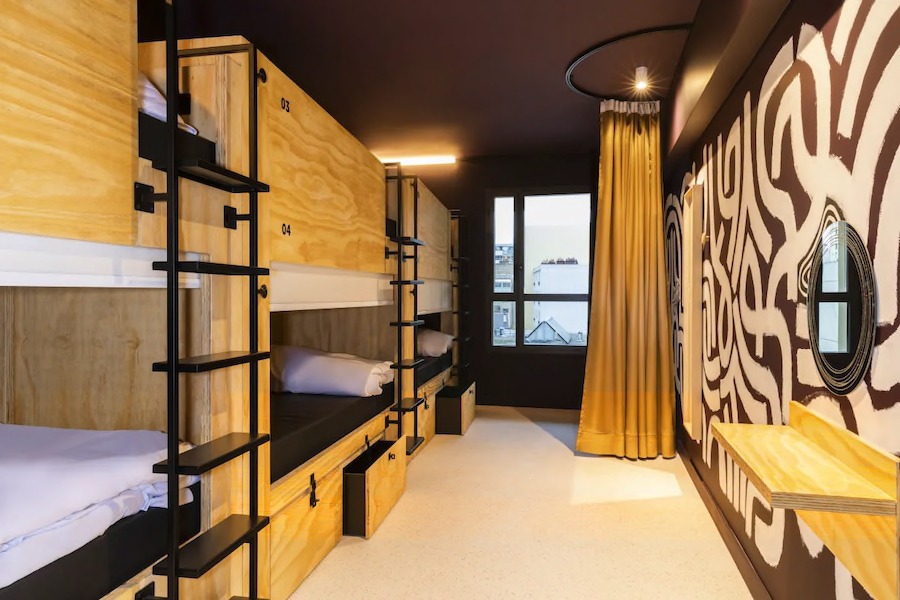 This is an image of a cool hostel bedroom with wooden bunk beds.
