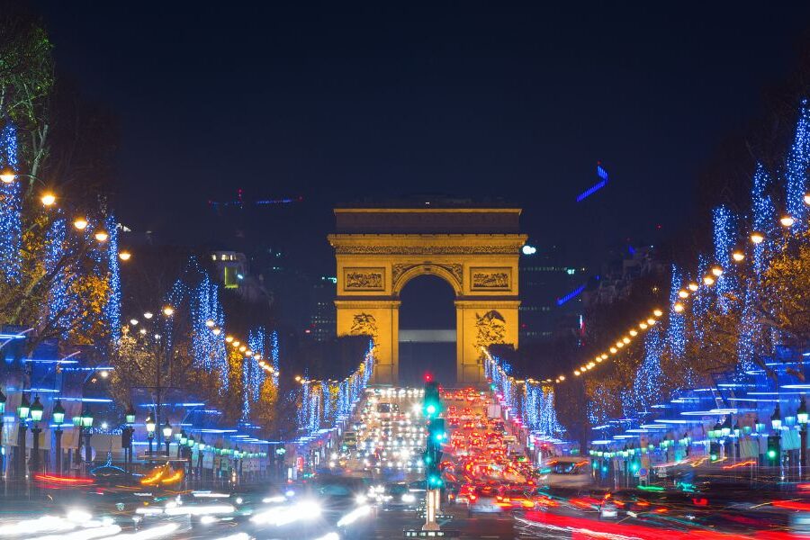This is an image of the Arc De Triomphe and Champs Elysees at night time with Christmas lights lining the boulevard.