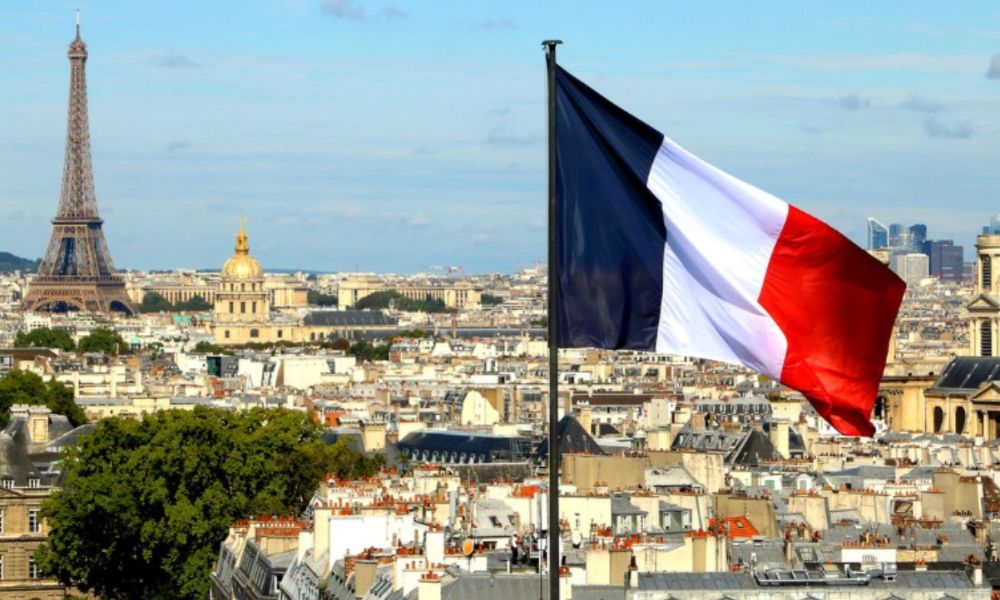 This is an image of a view of Paris from higher up on a building. The French flag is flying in the centre, and the Eiffel Tower is in the distance.