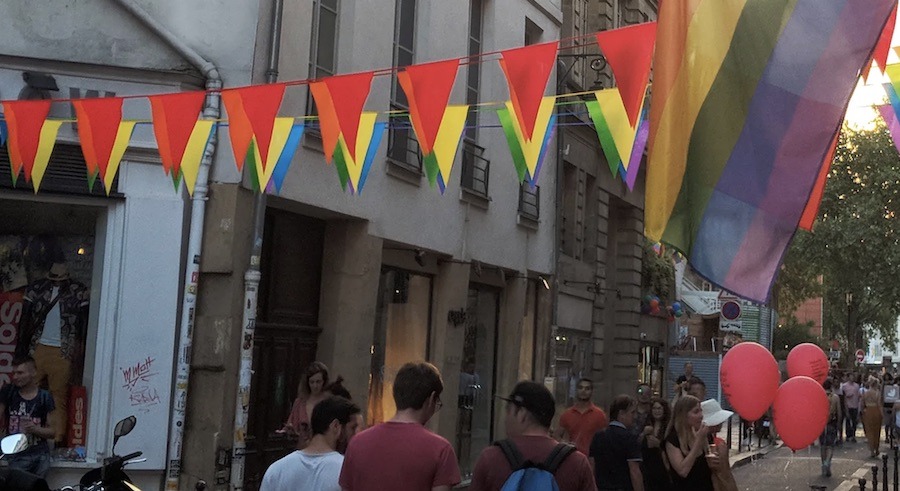 This is an image of a very bright street filled with colourful flags and the LGBTQIA flag as well.