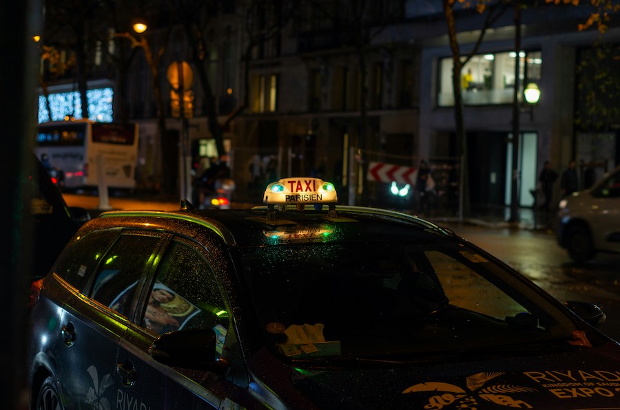 This is an image of a Paris taxi with its light on. It is night time, so you can't see much of the surroundings.