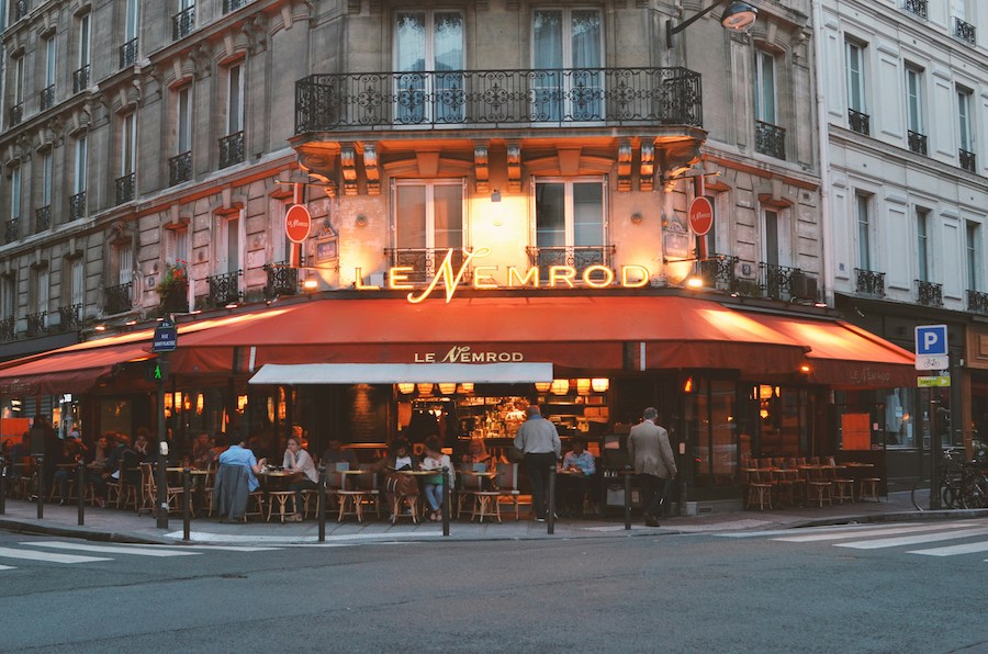 This is an image of a bistro in Paris with outdoor seating. It is quite full as it looks like a dinner service is about to begin.