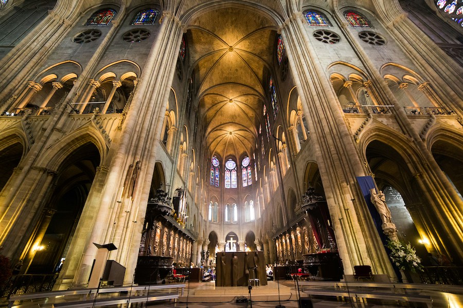 This is an image of the inside of Notre Dame de Paris and all the stained glass windows and high ceilings.
