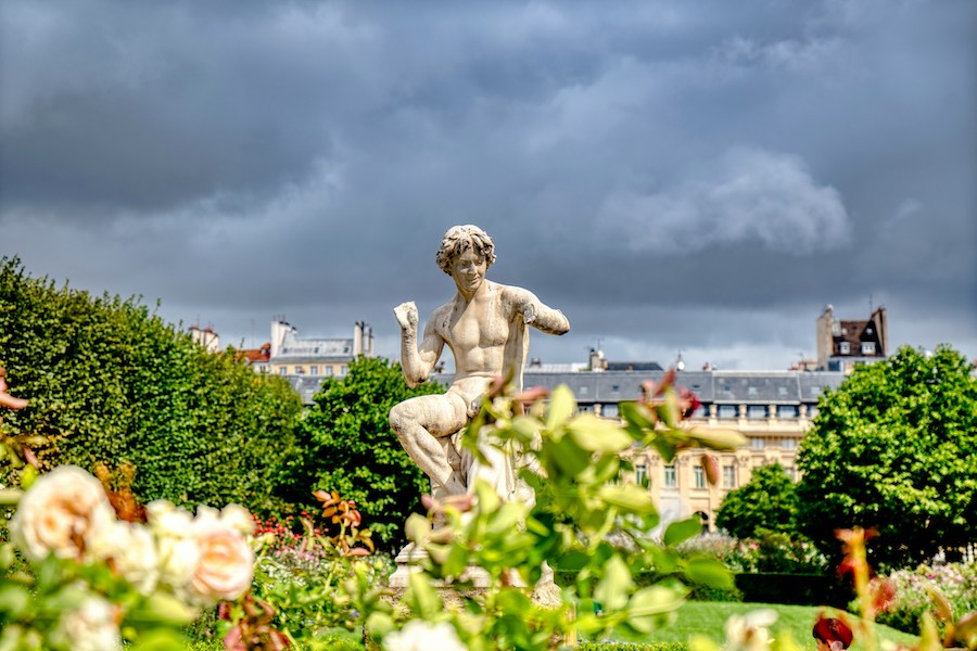 This is an image of a statue in the Tuileries Garden. In the foreground, there is a lot of greenery and trees. This is one of the most unique things to with kids in Paris.