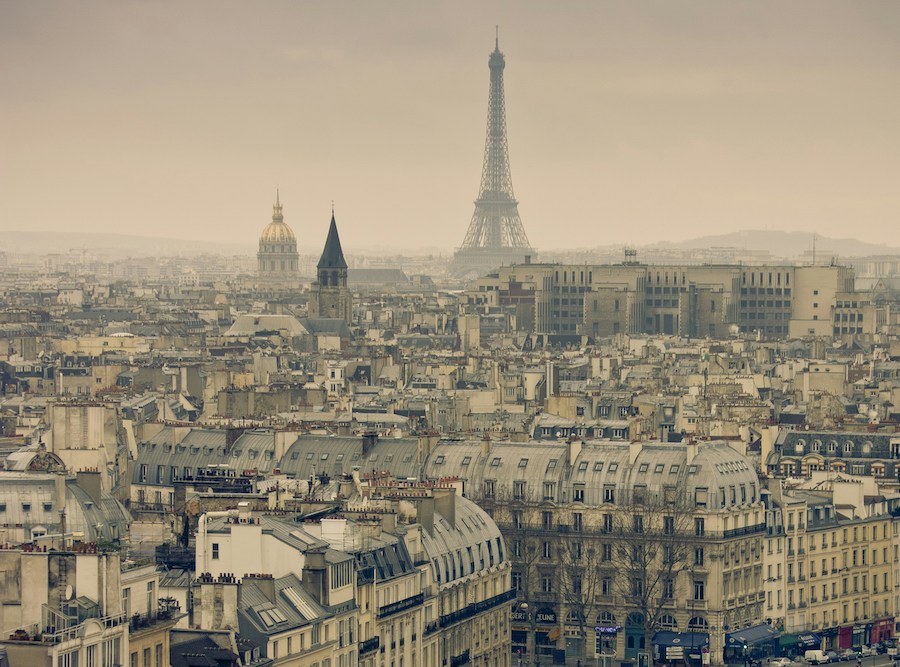 This is an image of Paris from a height. You can see lots of typical Parisien buildings, as well as the Eiffel Tower in the distance.