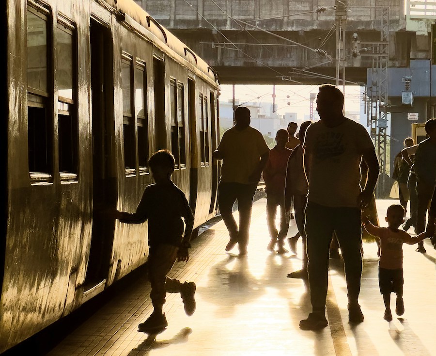 This is an image of two kids and their father running towards the train door.