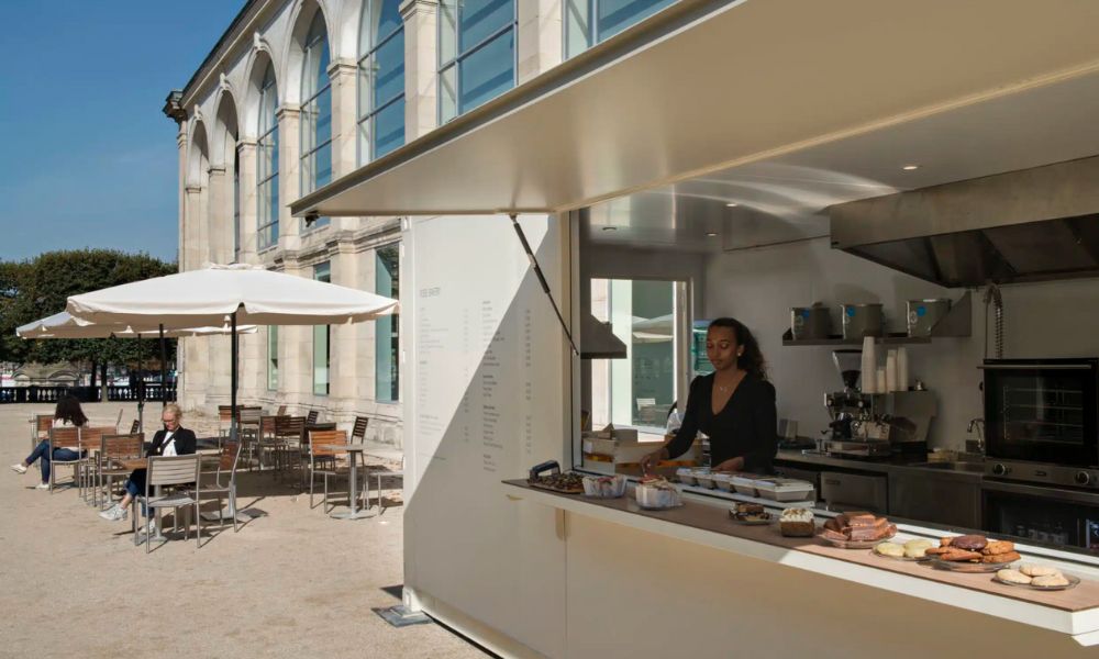 This is an image of a cafe on the terrace of a building in Paris where there is a viewpoint. It is a sunny day so the blue skies are out.