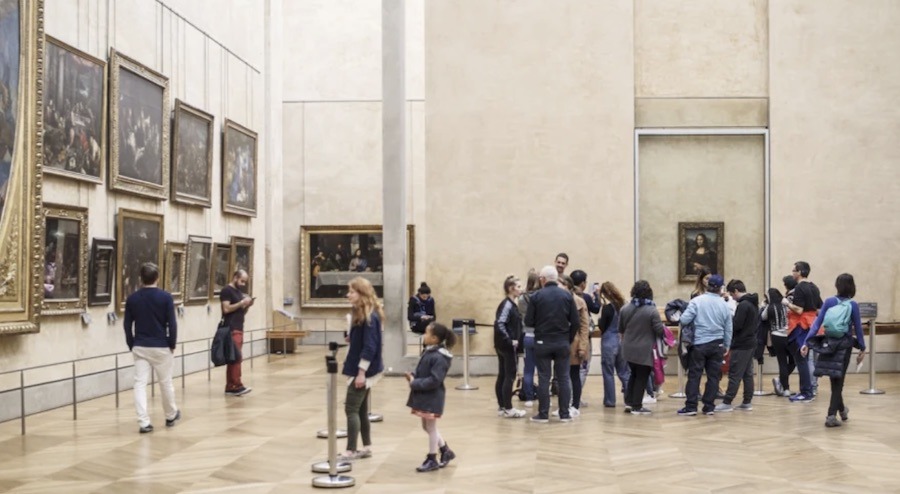 This is an image of a tour group inside The Louvre looking at The Mona Lisa.
