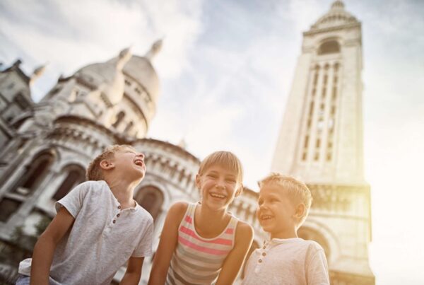 This is a picture of three kids laughing in front of the Sacre Coeur Cathedral.
