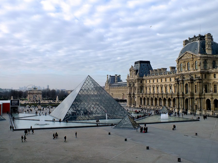This is a picture of the Louvre area in Paris. There are a few people milling around. An important thing to know before visiting Paris is that it's imperative to buy tickets beforehand if you don't want to get stuck in long lines.