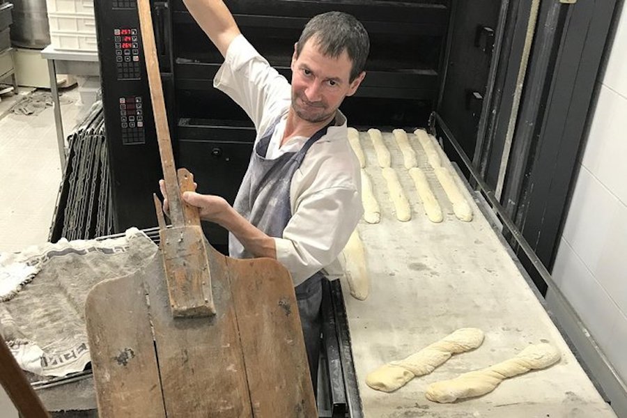 This is an image of a baker putting baguette dough into the oven.