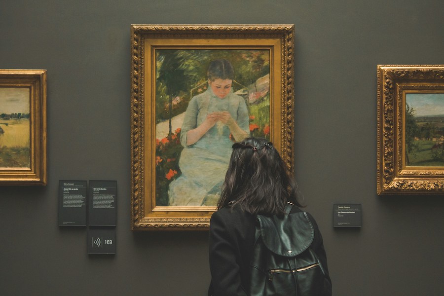 This is an image of a woman looking intently at a piece of artwork.