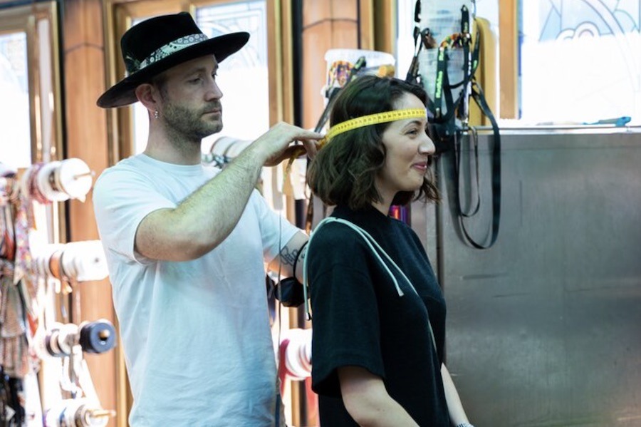 This is an image of a man measuring the circumference of a woman's head in order to make her a hat. Creating your own hat is a unique experience to try in Paris.
