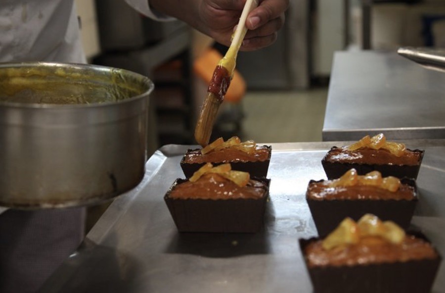 This is an image of a chef brushing fresh pastries with a wash or syrup.