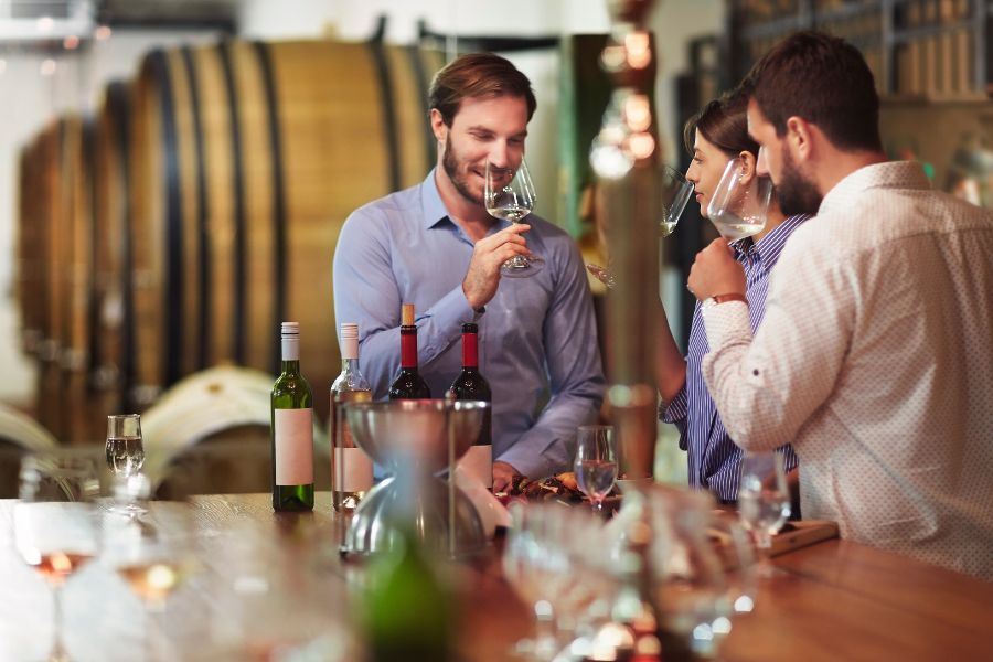 This is an image of three people enjoying wine at a table, while talking to one another.